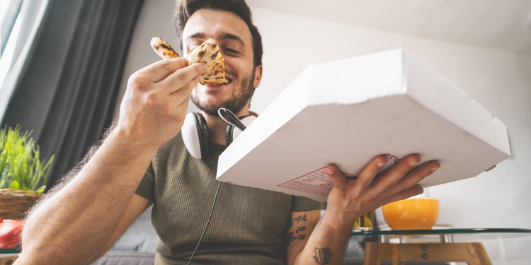 jeune homme mangeant une pizza