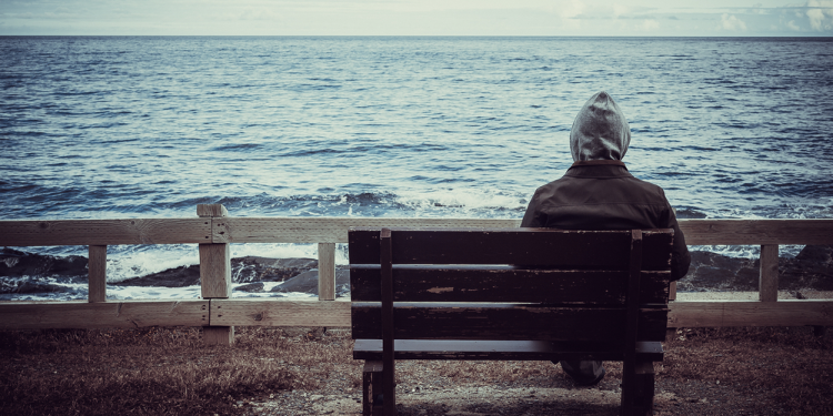 man sitting alone facing the sea