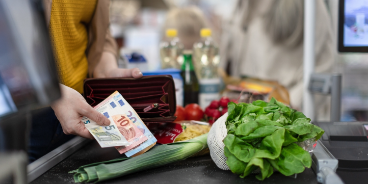 femme tenant des billets d'euros au supermarché