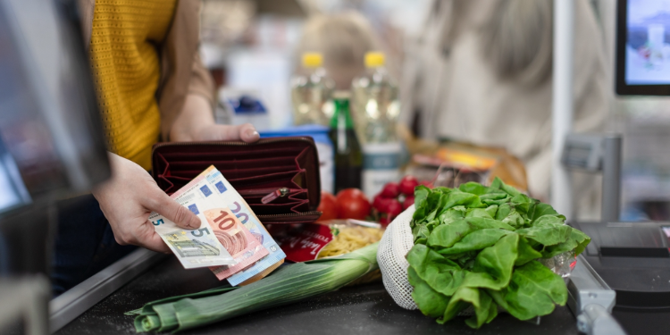 young woman holding bank notes at supermarket counter