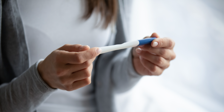 femme tenant un test de grossesse