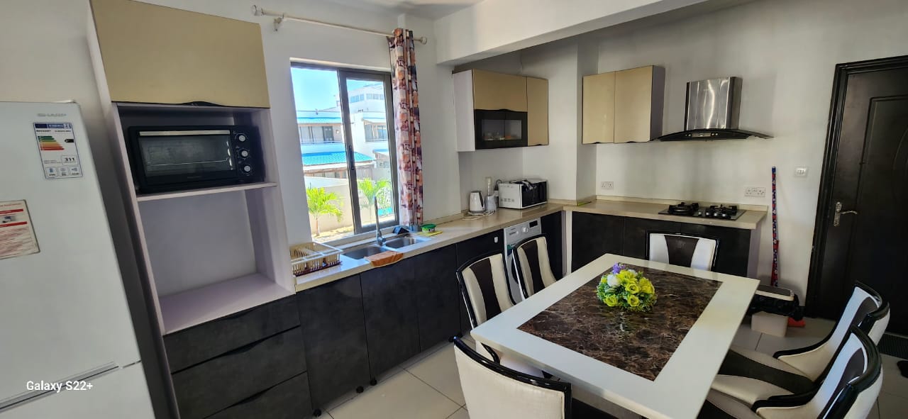 Bright, spacious apartment near the government school of Flic en Flac, with a fully equipped kitchen, rooftop pool access, and comfortable living spaces throughout.